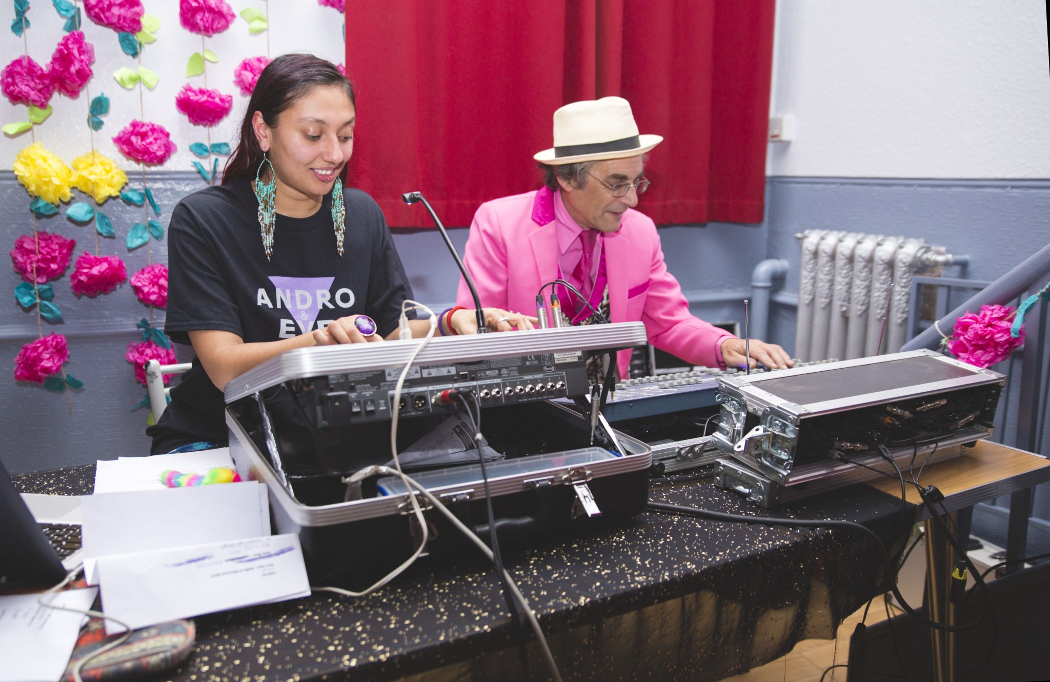 A volunteer operates the sound desk alongside our technician who is wearing a pink suit. 