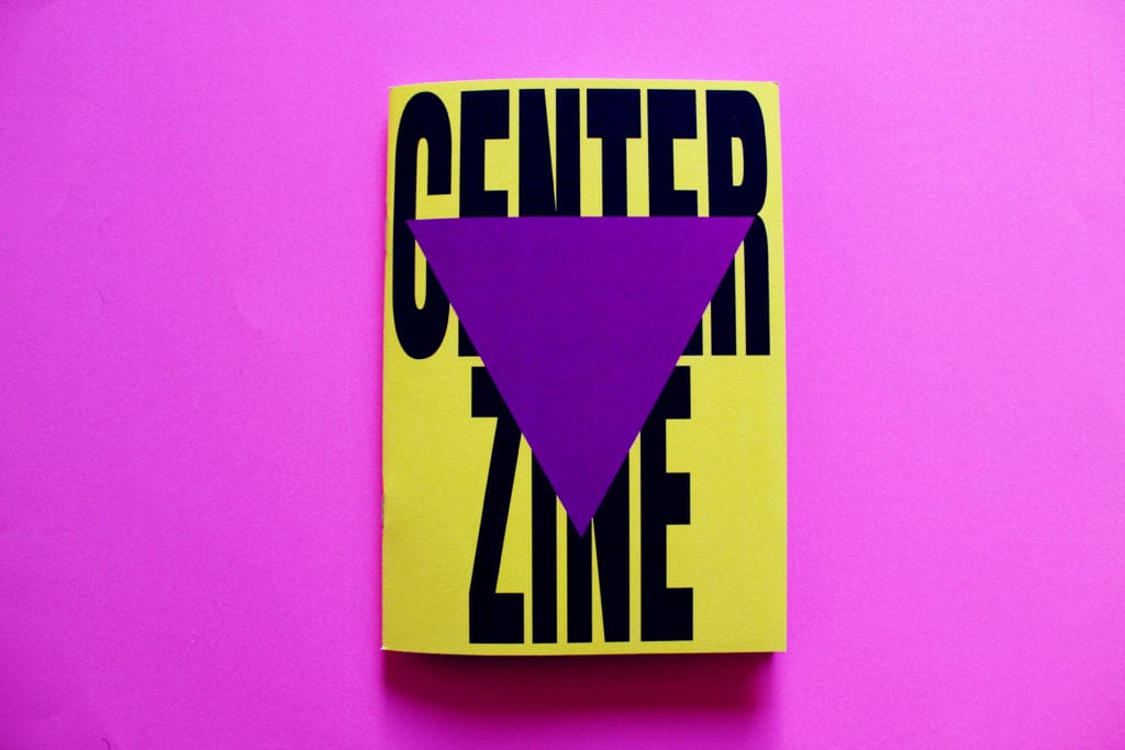 A bright yellow zine with the words Centre Zine, in bold, black lettering sits on top of a hot pink surface.