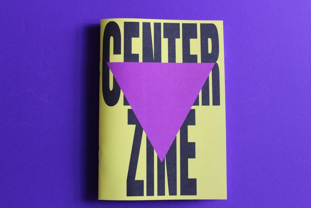An A5 bright yellow zine sits on a purple surface. It has the words 'Centre Zine' in bold black lettering across it with a plum triangle placed on top.