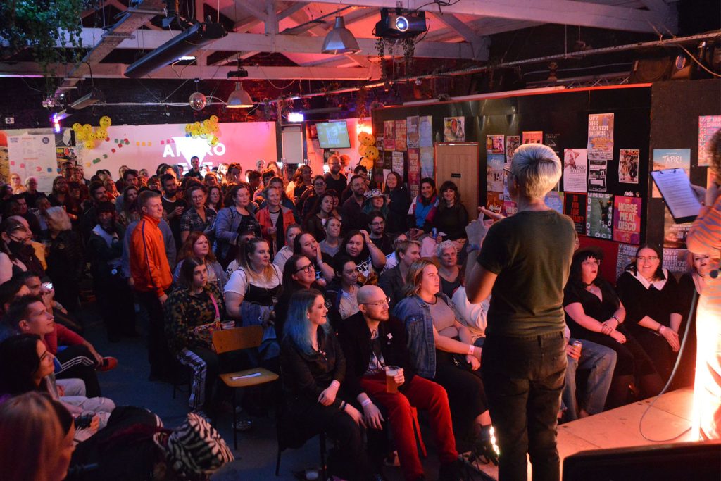 Crowd of people in a bar facing a stage