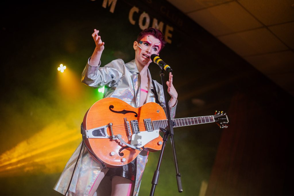 Drag King Ding Frisby sings with his guitar onstage in spacey costume