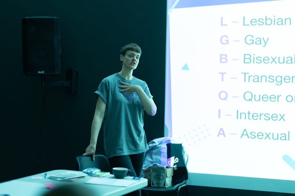 Finn is speaking in front of a screen with a session plan projected onto it