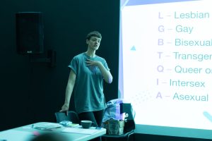 Finn is speaking in front of a screen with a session plan projected onto it