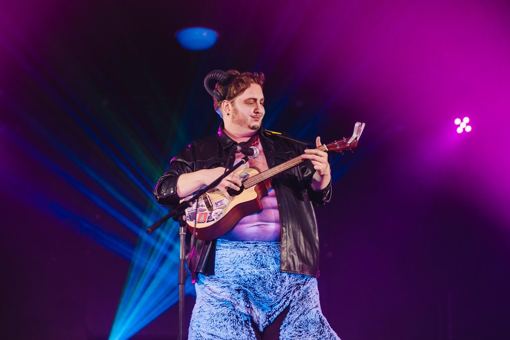 Drag king Awesome Swelles plays ukelele dressed as a satyr. He is a larger white performer