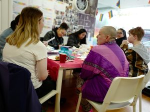 Kitt at table chatting to group of people doing crafts